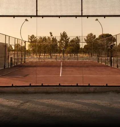 The padel court at golden hour, pines behind